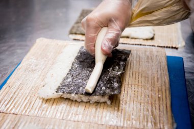 Restoranın mutfağında suşi ve ekmek yapma süreci. Şefin elleri bıçaklı..