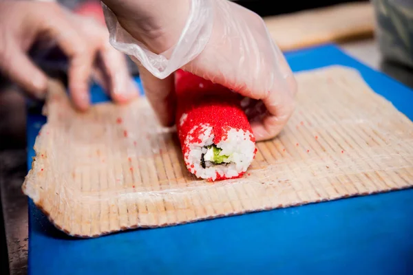 Processus de fabrication de sushis et de rouleaux à la cuisine du restaurant. Chefs mains avec couteau . — Photo