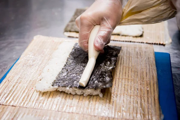 Proceso de hacer sushi y rollos en la cocina del restaurante. Chefs manos con cuchillo . —  Fotos de Stock