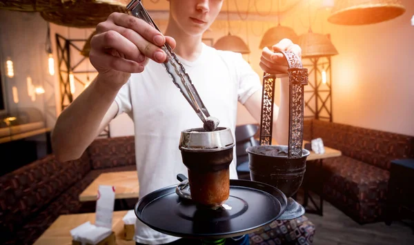 Cooking hookah in the bar. Young man with hookah in restaurant