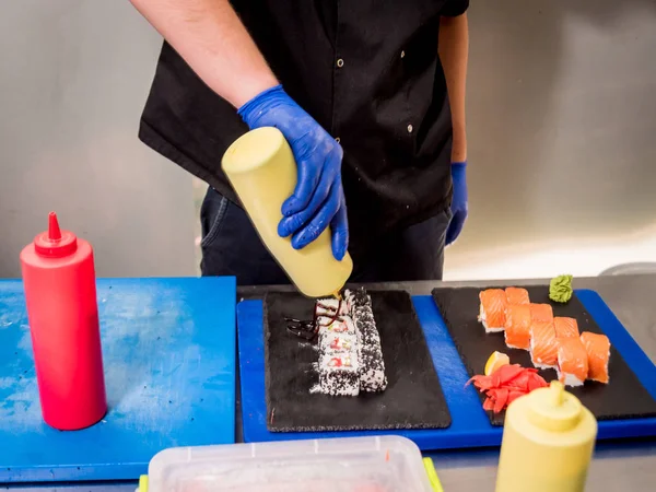 Processus de fabrication de sushis et de rouleaux à la cuisine du restaurant. Chefs mains avec couteau . — Photo