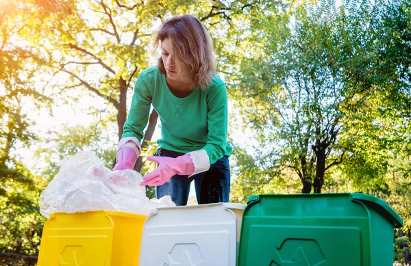 Volunteer girl sorts garbage in the street of the park. Concept of recycling. — ストック写真
