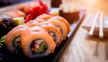 Suşi seti. Tahta bir tabakta somon, yılan balığı ve kırmızı havyarla yuvarlanıyor. Restoran.