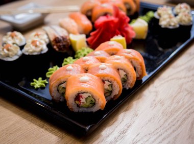 Suşi seti. Tahta bir tabakta somon, yılan balığı ve kırmızı havyarla yuvarlanıyor. Restoran.