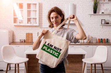 Young girl holding a cloth bag. At the kitchen. I am not plastic. 