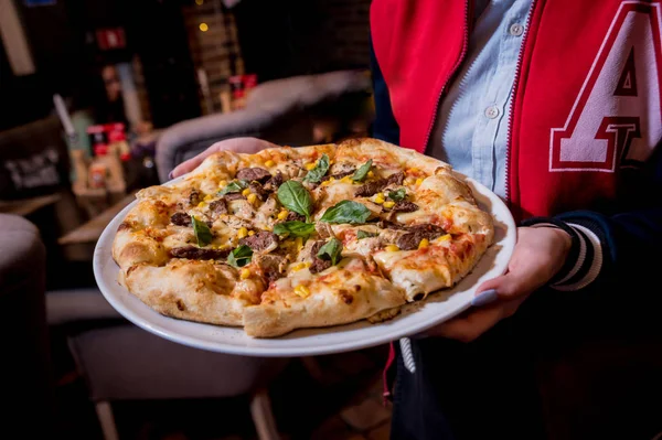 Serveur, portant un plat avec une délicieuse pizza avec du poulet et des légumes. Restaurant . — Photo