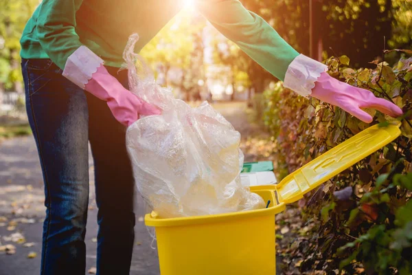 Volunteer girl sorts garbage in the street of the park. Concept of recycling. — ストック写真