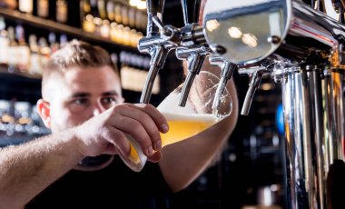 Barmen bardaklara bira dolduruyor. Restoran.