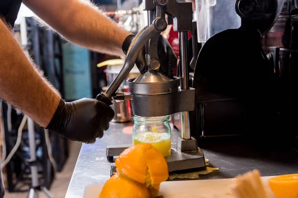 金属製の手動ジューサー。絞りたてのオレンジジュースの準備 — ストック写真