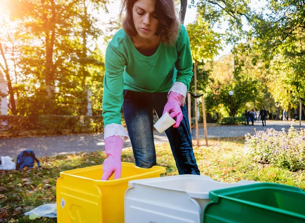 Volunteer girl sorts garbage in the street of the park. Concept of recycling. — ストック写真