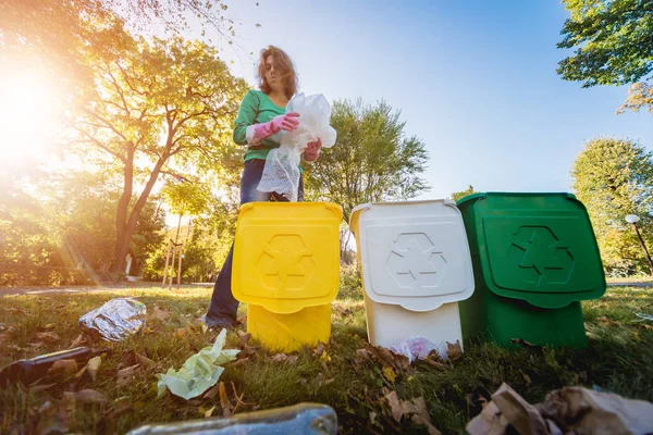 Volunteer girl sorts garbage in the street of the park. Concept of recycling. — ストック写真