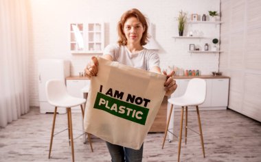 Young girl holding a cloth bag. At the kitchen. I am not plastic. 