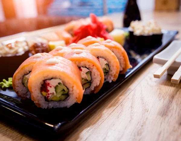Suşi seti. Tahta bir tabakta somon, yılan balığı ve kırmızı havyarla yuvarlanıyor. Restoran.