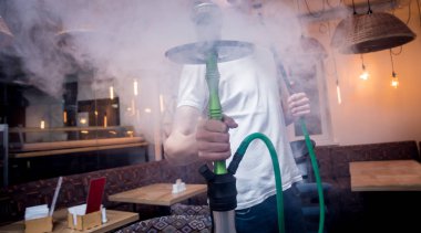 Barda nargile pişirmek. Lokantada nargilesi olan genç adam.