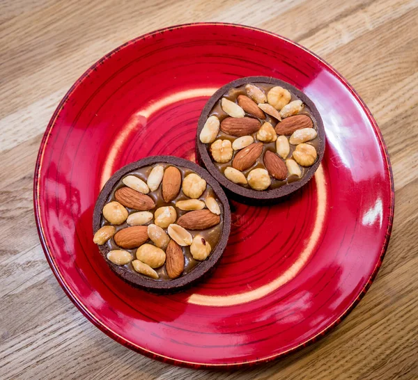 Chocoladekoekjes met amandelnoten op een rood bord. Restaurant. — Stockfoto