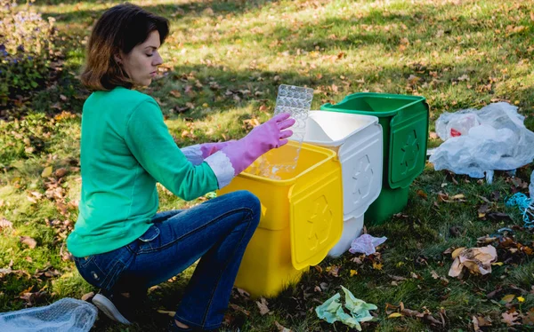 Volunteer girl sorts garbage in the street of the park. Concept of recycling. — ストック写真