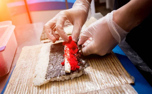 Proceso de hacer sushi y rollos en la cocina del restaurante. Chefs manos con cuchillo . — Foto de Stock
