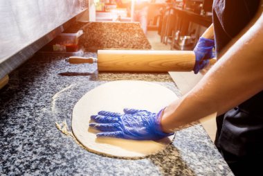 Pizza yapma süreci. Kafe mutfağında pizza yapan aşçının elleri.