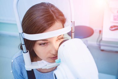 Doctor examining womans eyes with a measurement machine.