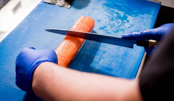 Proces výroby sushi a rolls v kuchyni restaurace. Šéfkuchaři ruce s nožem. — Stock fotografie
