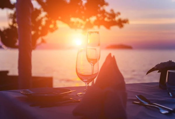 Copas de vino en la mesa del bar. Puesta de sol sobre el mar — Foto de Stock