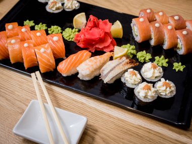 Suşi seti. Tahta bir tabakta somon, yılan balığı ve kırmızı havyarla yuvarlanıyor. Restoran.