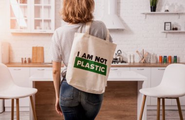 Young girl holding a cloth bag. At the kitchen. I am not plastic.