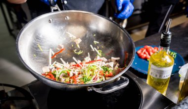 Şef tavada sebzeli makarna pişiriyor. İtalyan mutfağı. Restoran.