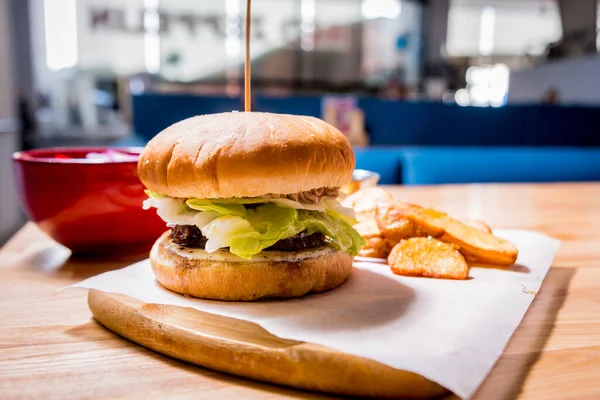 Cheeseburger saboroso e batatas fritas na mesa de madeira. Restaurante . — Fotografia de Stock