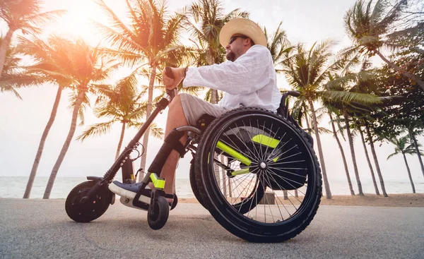 Disabled man in a wheelchair with electric scooter on the beach — Φωτογραφία Αρχείου