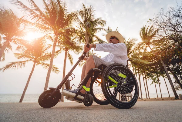 Disabled man in a wheelchair with electric scooter on the beach — 스톡 사진