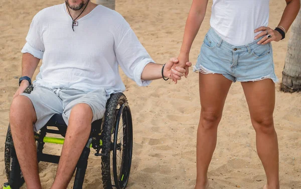 Homem deficiente em uma cadeira de rodas com sua esposa na praia . — Fotografia de Stock