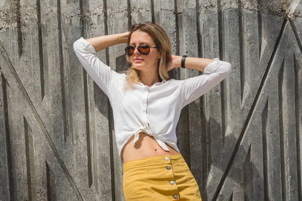 Giovane donna sexy in occhiali da sole posa vicino muro grigio . — Foto Stock