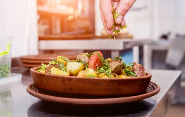 Koch kocht in Restaurantküche Bratkartoffeln mit Fleischstücken — Stockfoto