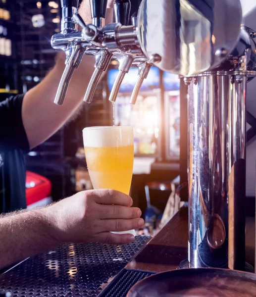 Barman schenkt tapbier in bij glazen in de bar. — Stockfoto