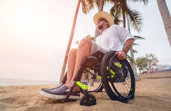 Disabled man in a wheelchair on the beach. — Stock fotografie