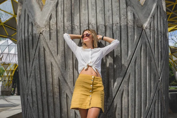 Jovem mulher sexy em óculos de sol posando perto da parede cinza . — Fotografia de Stock