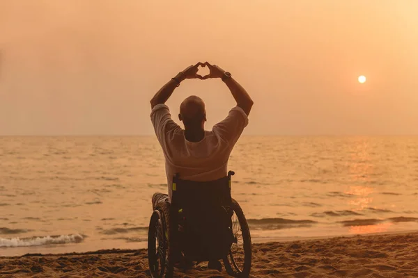 Disabled man in a wheelchair on the beach. — Stockfoto