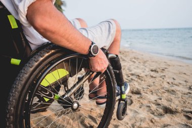 Disabled man in a wheelchair on the beach.