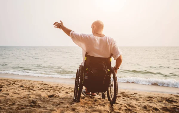 Disabled man in a wheelchair on the beach. — Stockfoto