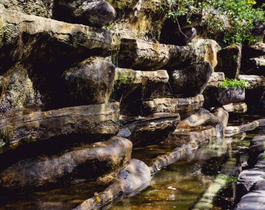 Botanik bahçesinde yapay şelale. Taşlar ve su.