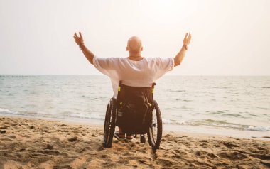 Disabled man in a wheelchair on the beach.