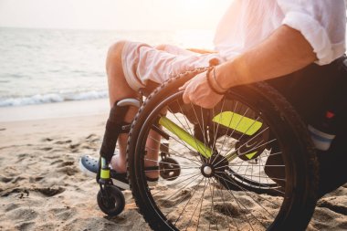 Disabled man in a wheelchair on the beach.