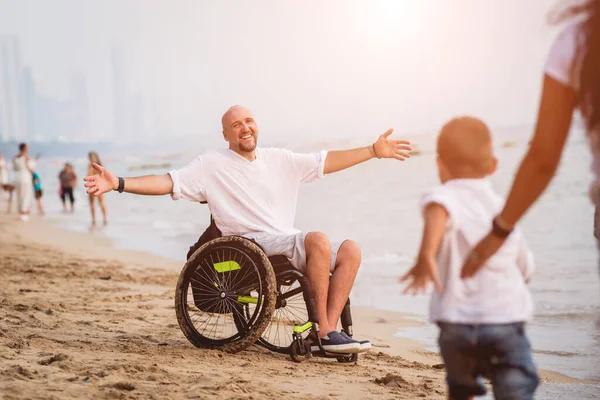 Disabled man in a wheelchair with his family on the beach. — Stockfoto