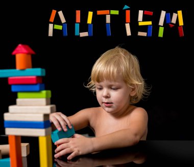 Otizm spektrum bozukluğu olan bir çocuk ahşap bir inşaatçıdan ev inşa eder. Otizm kavramı.