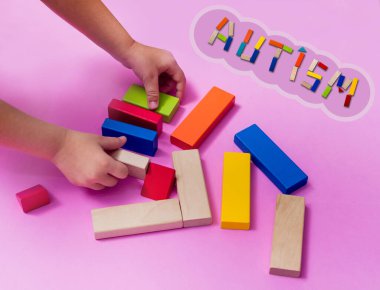 Otizm spektrum bozukluğu olan bir çocuk ahşap bir inşaatçıdan ev inşa eder. Otizm kavramı.