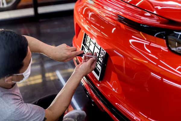 Técnico mudando o número da placa do carro no centro de serviço . — Fotografia de Stock