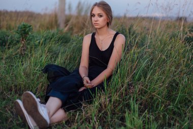 Gün batımında alanında siyah elbiseli ince kız