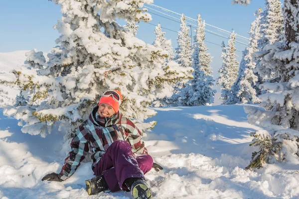 Retrato de una joven sonriente sentada en la nieve — Foto de Stock