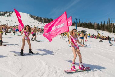 Grup genç mutlu güzel kadını bayrakları ile renkli bikini bir snowboard üzerinde.